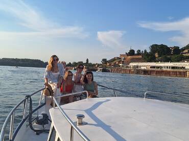 A group of friends enjoys a sunny day on a boat, capturing joyful moments together against a scenic backdrop — perfect for celebrations and outings on the water.