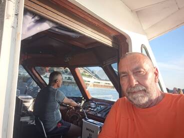 A selfie taken inside the helm of a boat, showcasing the captain at the controls and the intricate dashboard, perfect for those interested in boating experiences.