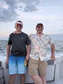 Two friends pose for a cheerful photo on a boat, enjoying their time at sea with smiles and stylish sunglasses — perfect for capturing memorable moments on the water.