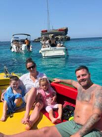 A joyful family enjoys a sunny day on a boat, with children playing and the beautiful turquoise waters in the background — perfect for family outings and aquatic adventures.