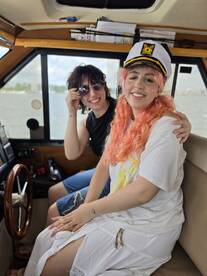 Two friends enjoy a moment inside the helm of a boat, showcasing a cozy cabin atmosphere perfect for navigating the waters.