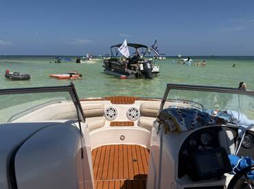 A lively scene at the beach with guests enjoying the water and various boats anchored nearby, perfect for a fun day out on the water.