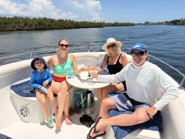 A joyful family enjoys drinks and snacks on a boat, celebrating together in the sun — perfect for memorable outings on the water.