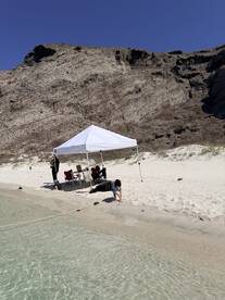 A family enjoys a sunny day at the beach under a tent, with children playing by the water's edge — perfect for a relaxing day of fun and exploration.
