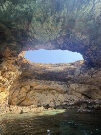 A stunning view of a natural cave with a hole in the ceiling, showcasing the beautiful rock formations and turquoise waters below — a perfect spot for exploration and adventure.