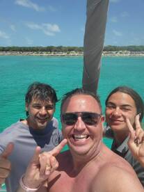 A joyful group takes a selfie on a boat, showcasing the stunning turquoise waters in the background — perfect for capturing memorable moments on a fun day out at sea.