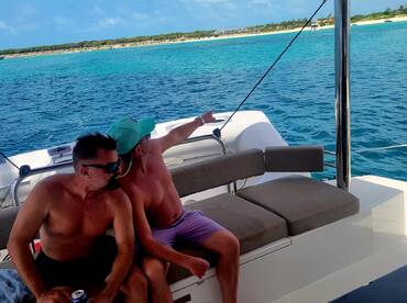Two friends enjoy a relaxing moment on a boat, pointing out the beautiful ocean scenery — a perfect snapshot of leisure and adventure on the water.
