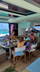 A family enjoys a meal together in the cozy dining area of a boat, surrounded by stunning ocean views — perfect for memorable dining experiences on the water.