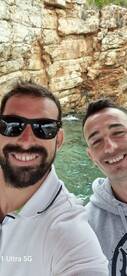 Two friends take a cheerful selfie while enjoying a boating adventure, surrounded by stunning rocky scenery — perfect for capturing memorable moments on the water.