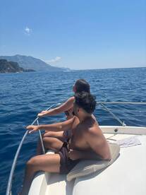 A couple enjoys a scenic view from the bow of a boat, soaking in the sun and ocean breeze — perfect for romantic getaways or adventurous outings on the water.
