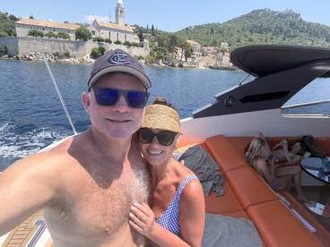 A couple enjoys a sunny day on a boat, with scenic views in the background — perfect for memorable outings and celebrations on the water.