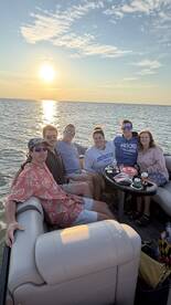 A cheerful group enjoys a sunset cruise on a pontoon boat, capturing the perfect moment of camaraderie and relaxation on the water.