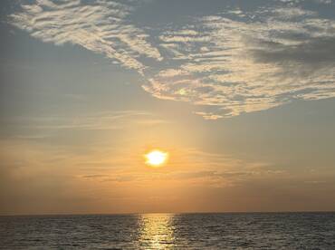 A serene sunset over the ocean, reflecting golden hues on the water's surface — a perfect backdrop for evening boat cruises.