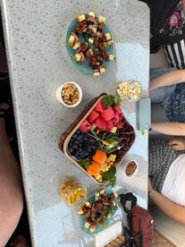 A beautifully arranged spread of fruits, snacks, and charcuterie on a boat table, perfect for enjoying refreshments while cruising on the water.