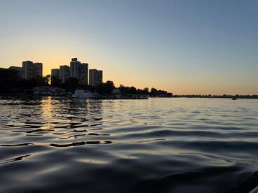 A serene sunset view over the water, showcasing a city skyline and reflecting golden hues — perfect for capturing the beauty of urban waterfronts.