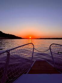 A stunning sunset view from the bow of a boat, showcasing tranquil waters and a vibrant sky — perfect for evening cruises.