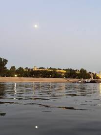 A serene evening view of the moon reflecting on the water, with a picturesque landmark in the background — perfect for capturing the beauty of a tranquil night on the water.