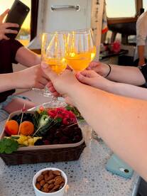 A group toasts with cocktails while enjoying a vibrant spread of fresh fruit and snacks aboard a boat, capturing the essence of a festive celebration on the water.