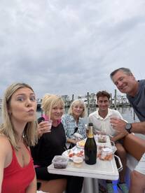 A cheerful group enjoys a boat party with cocktails and delicious food, capturing the essence of fun and celebration on the water.