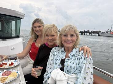 A cheerful group of friends enjoys drinks and snacks on a boat, capturing a perfect moment of camaraderie on the water.