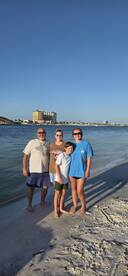 A cheerful family poses for a photo on the beach, capturing a memorable moment during their seaside adventure.