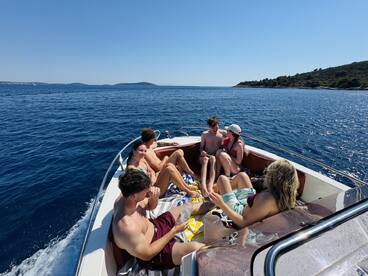 A lively group enjoys a sunny day on a boat, relaxing and soaking up the sun — perfect for summer outings and fun on the water.