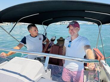 Two men enjoy a sunny day on a boat, showcasing a relaxed atmosphere on the water — perfect for a fun day out with friends.