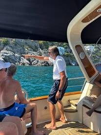 A group of guests aboard a boat enjoy the scenic views, with one person pointing out an interesting sight along the coastline. Perfect for capturing memorable moments on the water.