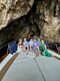 A cheerful group poses for a photo aboard a boat inside a stunning cave, capturing a memorable moment during their adventure.