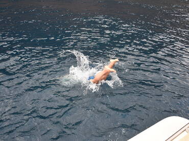 A child joyfully jumps into the water, creating a splash — a perfect moment of fun and excitement during a day on the boat.