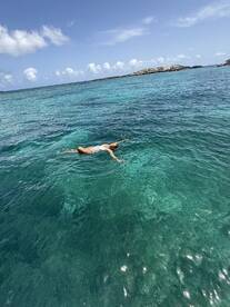 A woman enjoys a refreshing swim in the crystal-clear waters, showcasing the beauty of a tropical paradise — perfect for adventure seekers and beach lovers.