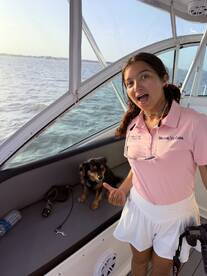 A young girl joyfully poses on a boat with her dog, capturing a fun moment on the water. Perfect for showcasing family-friendly boating adventures.