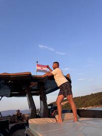 A man proudly raises the Croatian flag on a boat, capturing a moment of celebration on the water — perfect for showcasing the joy of boating in Croatia.