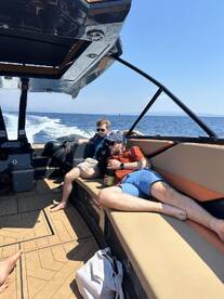 Two friends relax on the deck of a boat under the sun, enjoying a leisurely day on the water — perfect for summer outings and bonding moments.