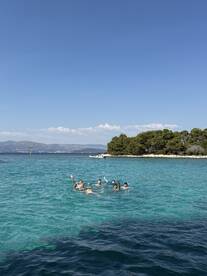 A lively group enjoys a refreshing swim in crystal-clear waters, showcasing the perfect summer day on the beach.