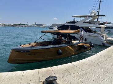A stylish boat is docked with a woman standing on the deck, showcasing the vibrant marina scene — perfect for luxury yacht experiences.