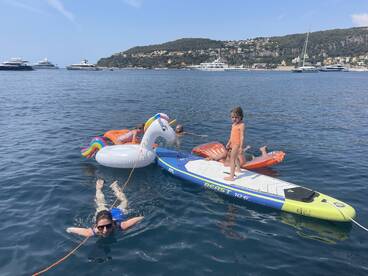 A fun day on the water with a group enjoying inflatable floats and paddleboarding, perfect for family adventures and summer outings.