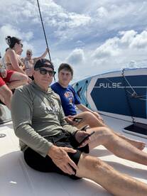 A group of friends relaxes on the deck of a boat under a sunny sky, enjoying their time together on the water.