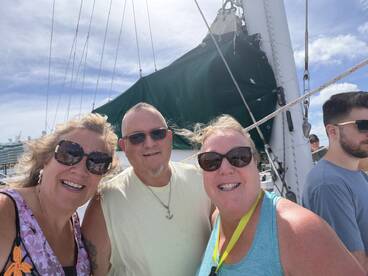 A cheerful group of friends poses for a selfie aboard a sailing vessel, capturing the joy of their boating experience.