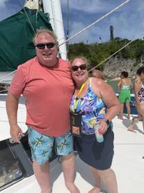 A cheerful couple poses for a photo on a boat, enjoying drinks and the sunny atmosphere — perfect for memorable moments on the water.
