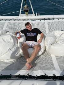 A young man relaxes on a bean bag aboard a boat, enjoying the sun and sea — a perfect moment for leisure on the water.