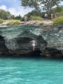 A group of friends enjoys a thrilling cliff diving experience into the crystal-clear waters, capturing the excitement of summer adventures.