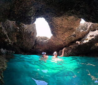 Two snorkelers explore a stunning underwater cave, surrounded by crystal-clear turquoise waters — a perfect adventure for marine enthusiasts.