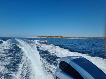 A thrilling moment captured as a skier glides over the water, showcasing the excitement of water sports against a beautiful coastal backdrop.