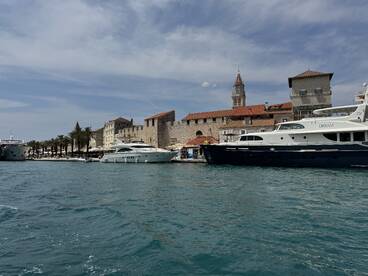A picturesque view of luxurious yachts docked at a charming harbor, showcasing the beautiful coastal architecture and vibrant palm trees.