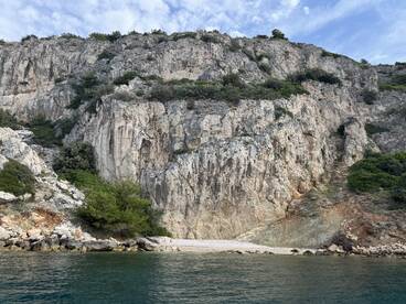 A stunning view of rocky cliffs meeting the tranquil waters, showcasing the natural beauty of the coastline — perfect for exploring hidden beaches and scenic boat trips.