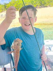 A joyful child proudly displays his catch while fishing on a boat, capturing the excitement of outdoor adventures and family fun on the water.