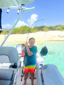 Two kids enjoy a fun fishing experience aboard a boat, showcasing the excitement of water activities in a beautiful setting.