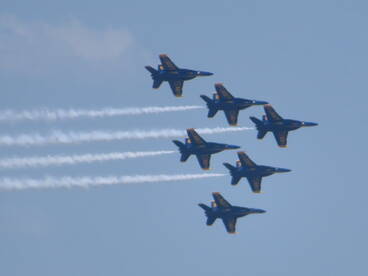 A formation of jets performing aerial maneuvers, showcasing precision flying in a clear blue sky.