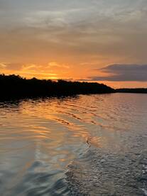 A stunning sunset reflects on the calm waters, creating a picturesque scene perfect for evening boat trips or romantic getaways.